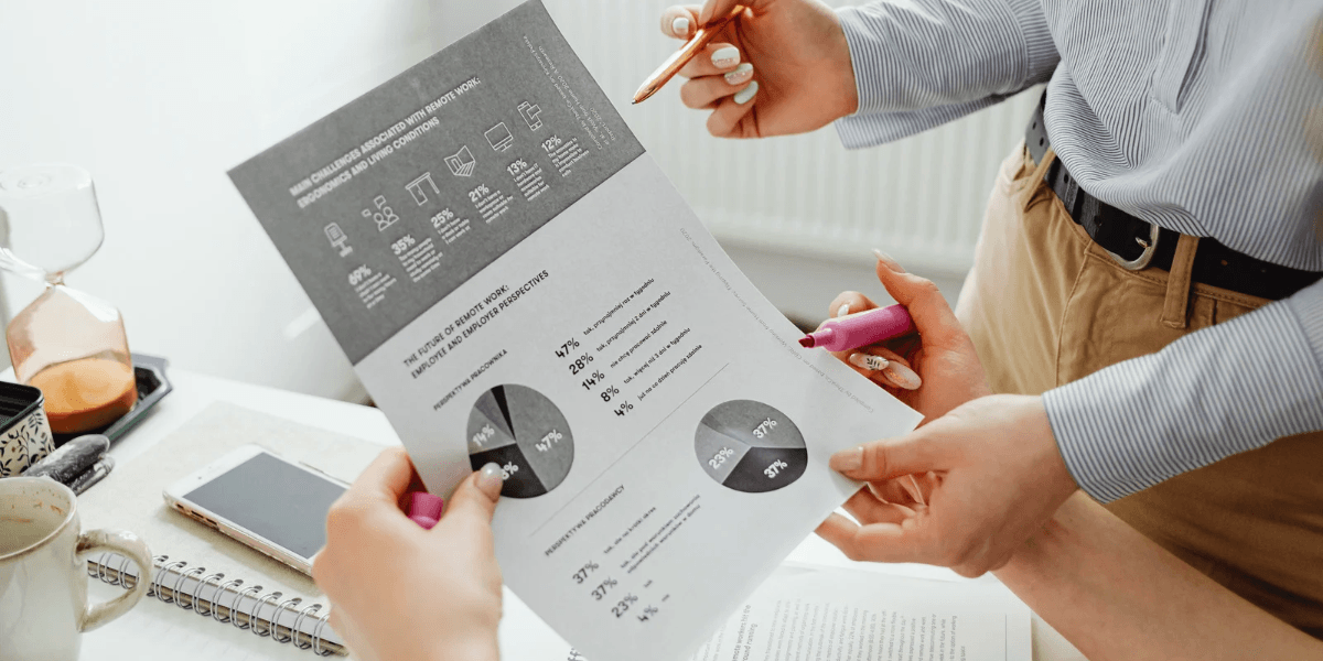 Two people discussing a report with charts in a workspace setting
