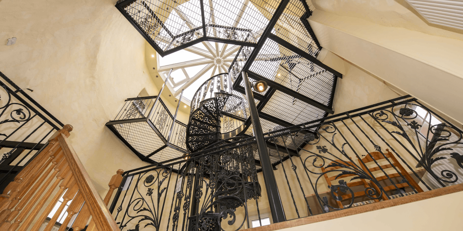 Spiral staircase inside The Witches Mill, blending intricate wrought ironwork with wooden accents and offering panoramic views.