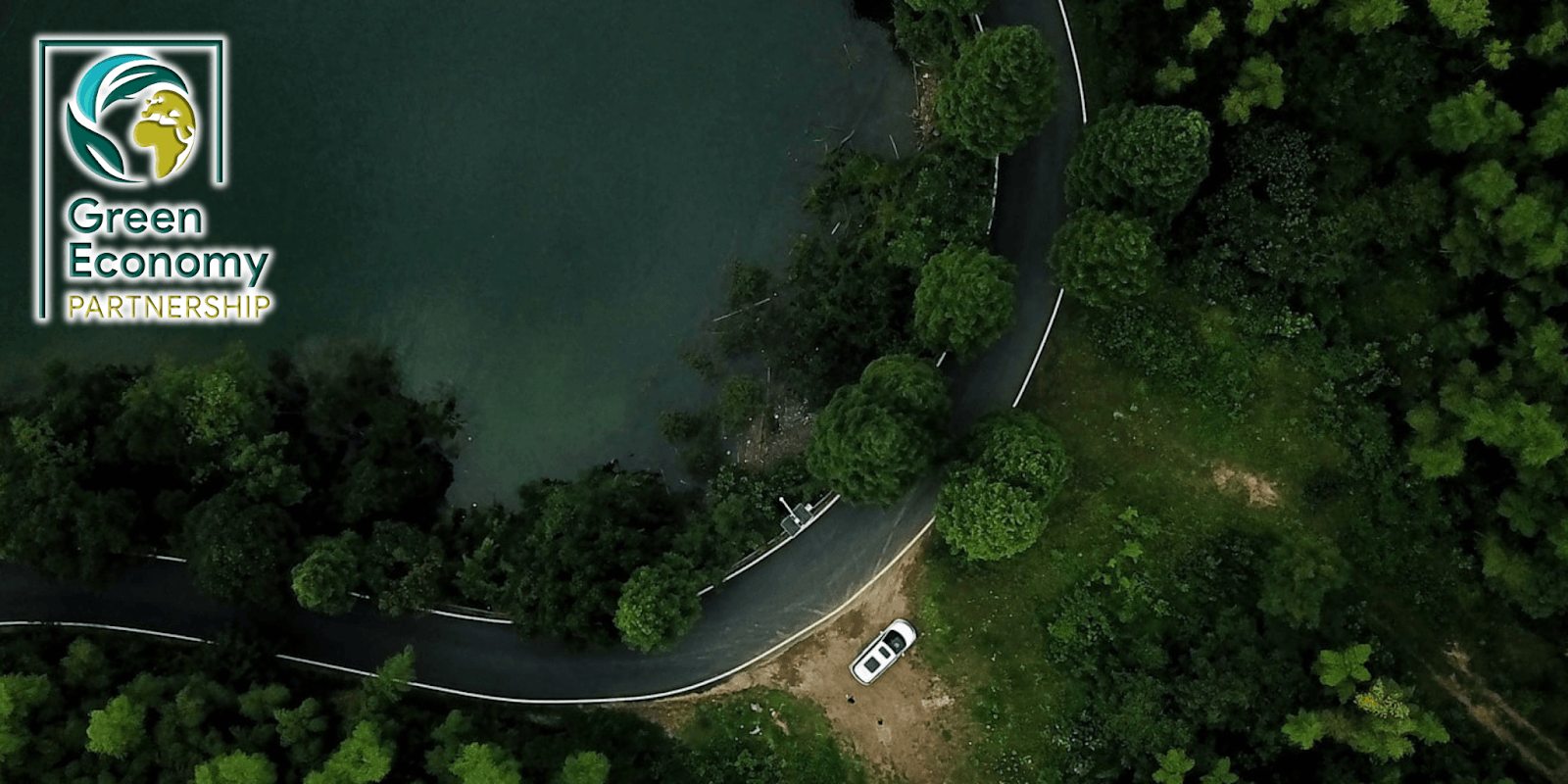 Aerial view of forest road beside lake with Green Economy Partnership logo, symbolizing AI-driven sustainable climate action.