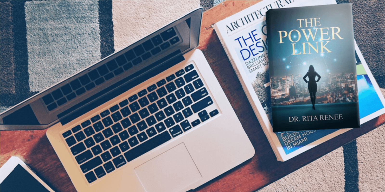 Image of Dr. Rita Renee's book The Power Link beside a laptop and architectural magazines.