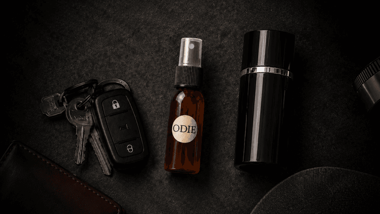 A brown spray bottle labeled "ODIE" alongside car keys and a black container