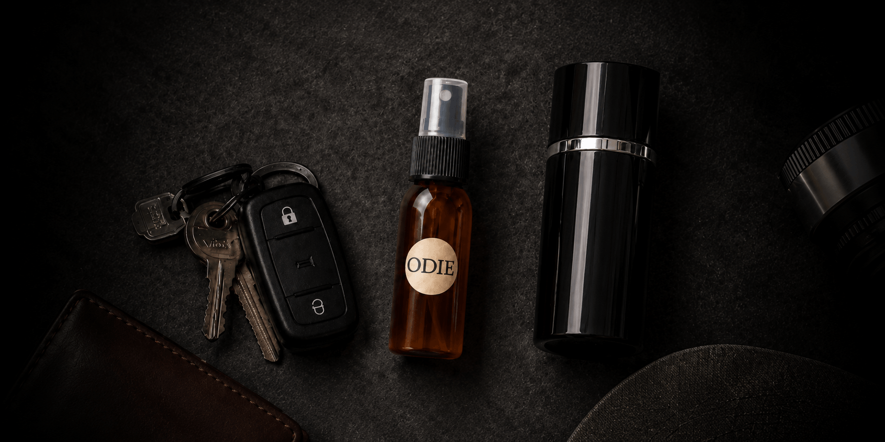 A brown spray bottle labeled "ODIE" alongside car keys and a black container
