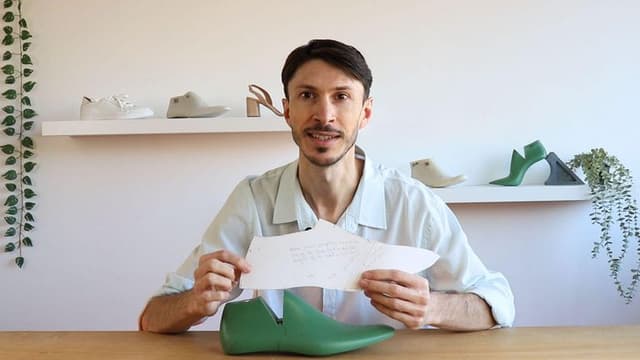 Man holding a shoe pattern in front of various shoe models on a shelf