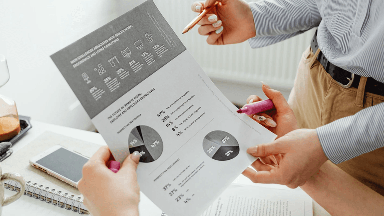 Two people discussing a report with charts in a workspace setting