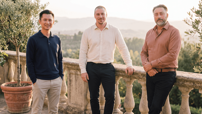 Three men standing together on a balcony with a scenic outdoor backdrop