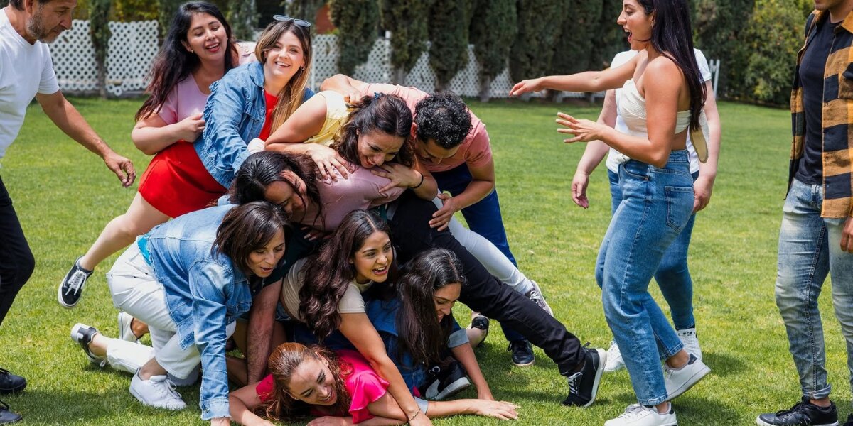 Group of friends laughing together during an outdoor team activity on the grass.