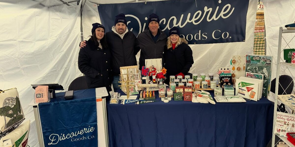Four team members at Discoverie Goods Co booth displaying candles, gifts, and local products during Havertown pop-up event promotion community