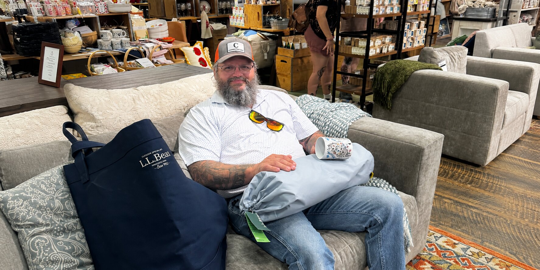 Justin Curatola seated on a sofa in a home furnishings showroom.