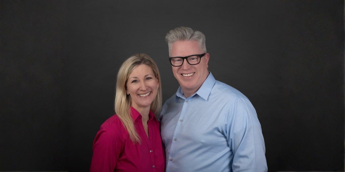 A smiling woman in a pink shirt and a man in a blue shirt stand together, embodying Compassion Processing's values of transparency and purpose.