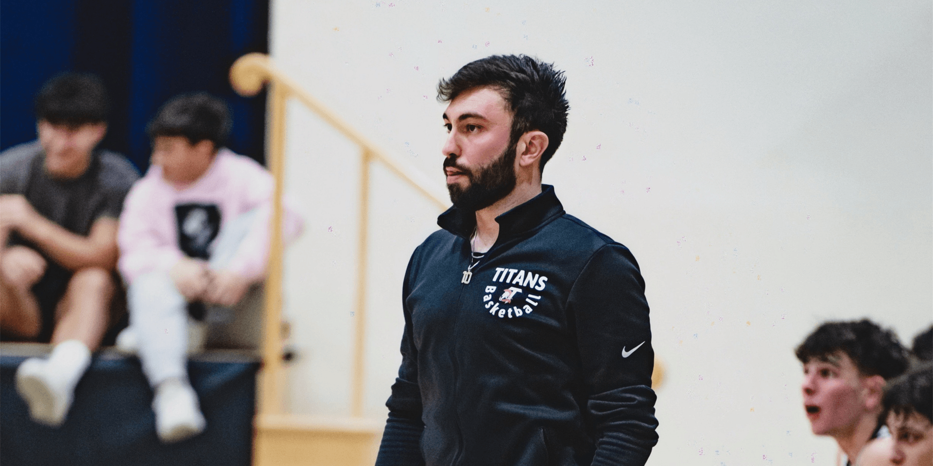 Coach reviewing plays on clipboard courtside during a basketball game.