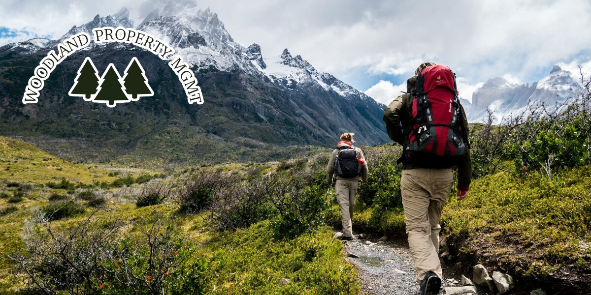 Hikers on mountain trail beneath rugged peaks, representing outdoor lifestyle near Vail Valley properties.