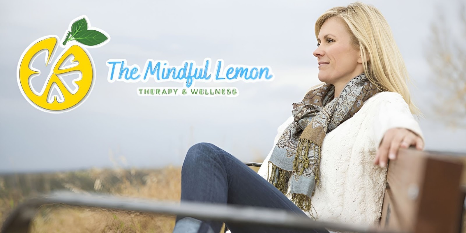 A woman sitting outdoors on a bench, reflecting calmly, representing The Mindful Lemon's focus on thoughtful mental health care.