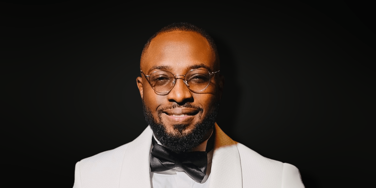 John Onifade, founder of Sweftly, a chat-first global payments platform, smiles confidently in a formal white suit and bow tie, embodying the company’s mission to simplify cross-border money transfers through AI and automation.