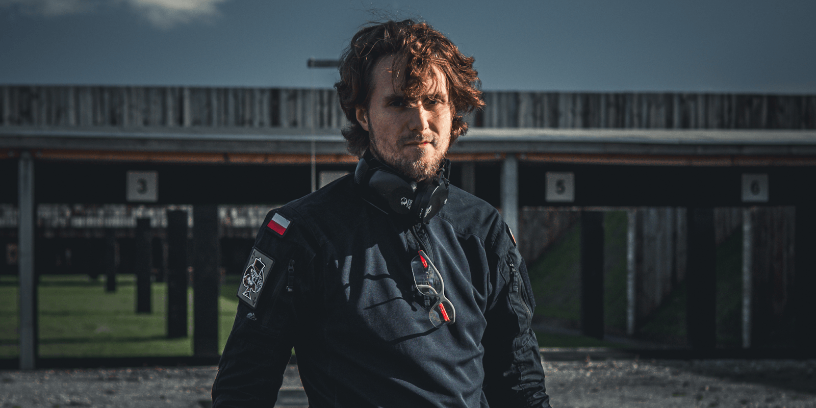 Łukasz Bugajski, founder of Bugajski Consulting, stands in front of military equipment, exemplifying expertise in high-risk security solutions.