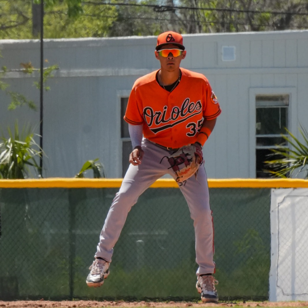 Baseball player Alfredo Velasquez in Orioles uniform, standing on the field.