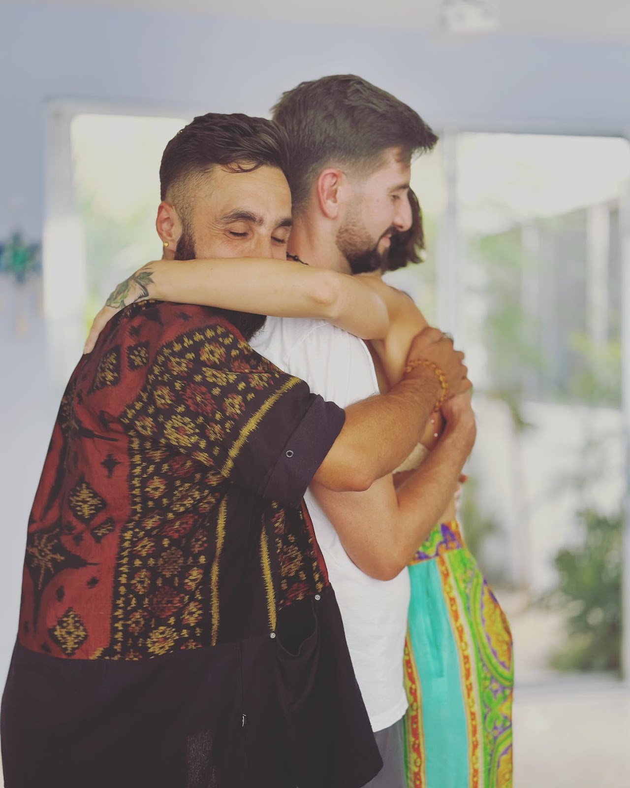 A heartfelt moment of three people embracing each other in a cozy, light-filled room, conveying a sense of love and connection.