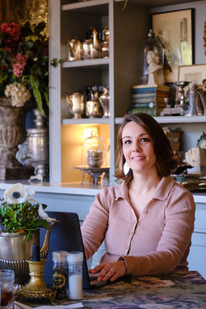 A woman sitting at a desk with a laptop in a cozy, decorated room.