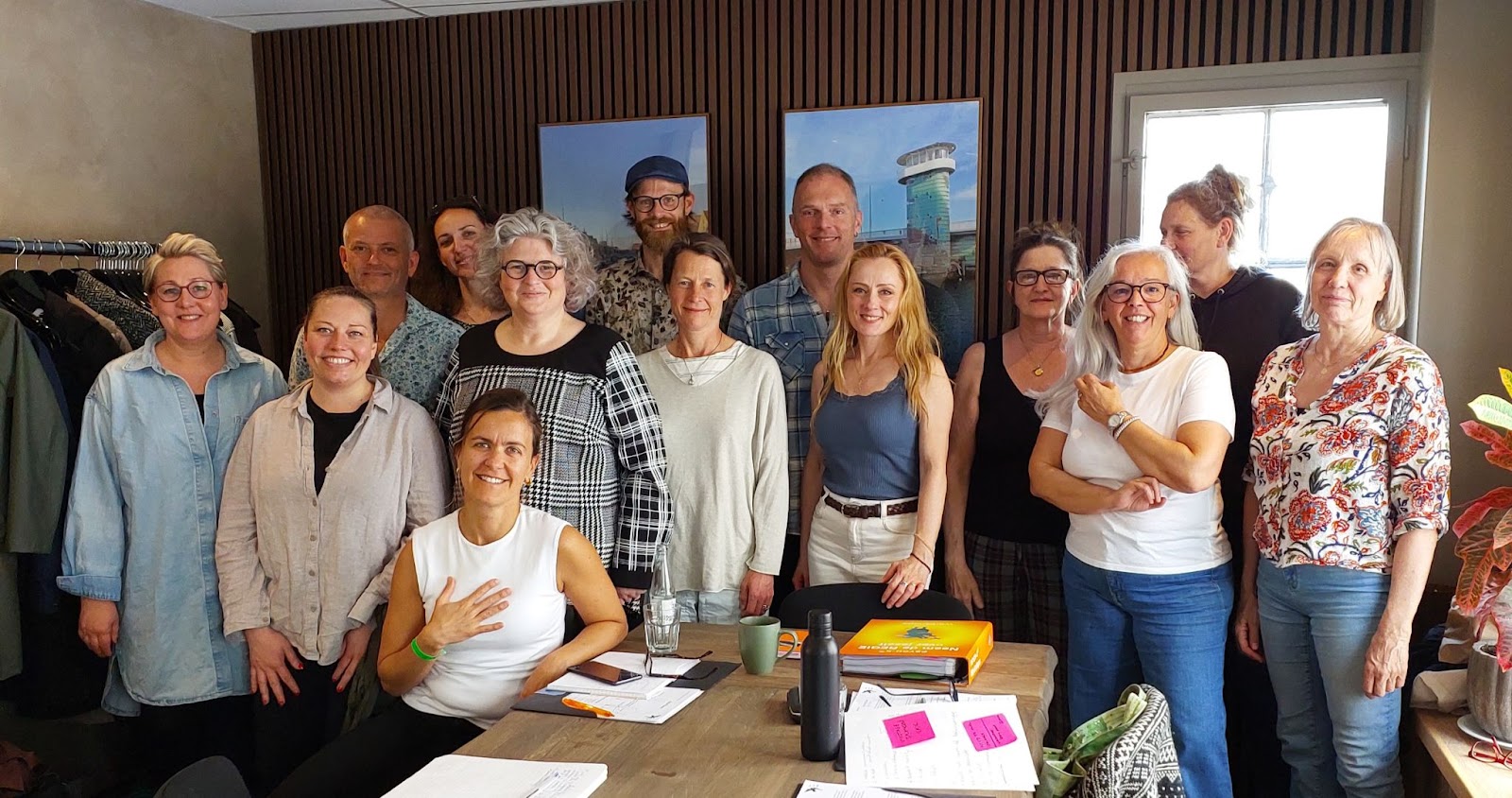 Group of professionals smiling and posing together in an office setting, showcasing teamwork and collaboration in a modern workspace.