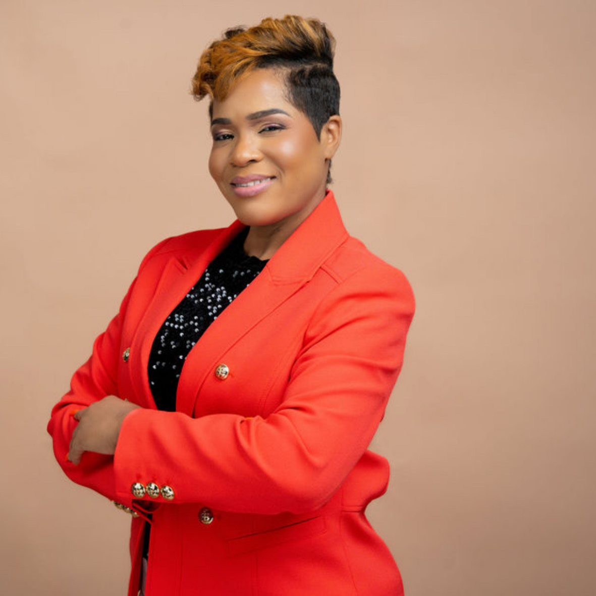 Professional portrait of a woman in a red blazer posing confidently against a neutral background.