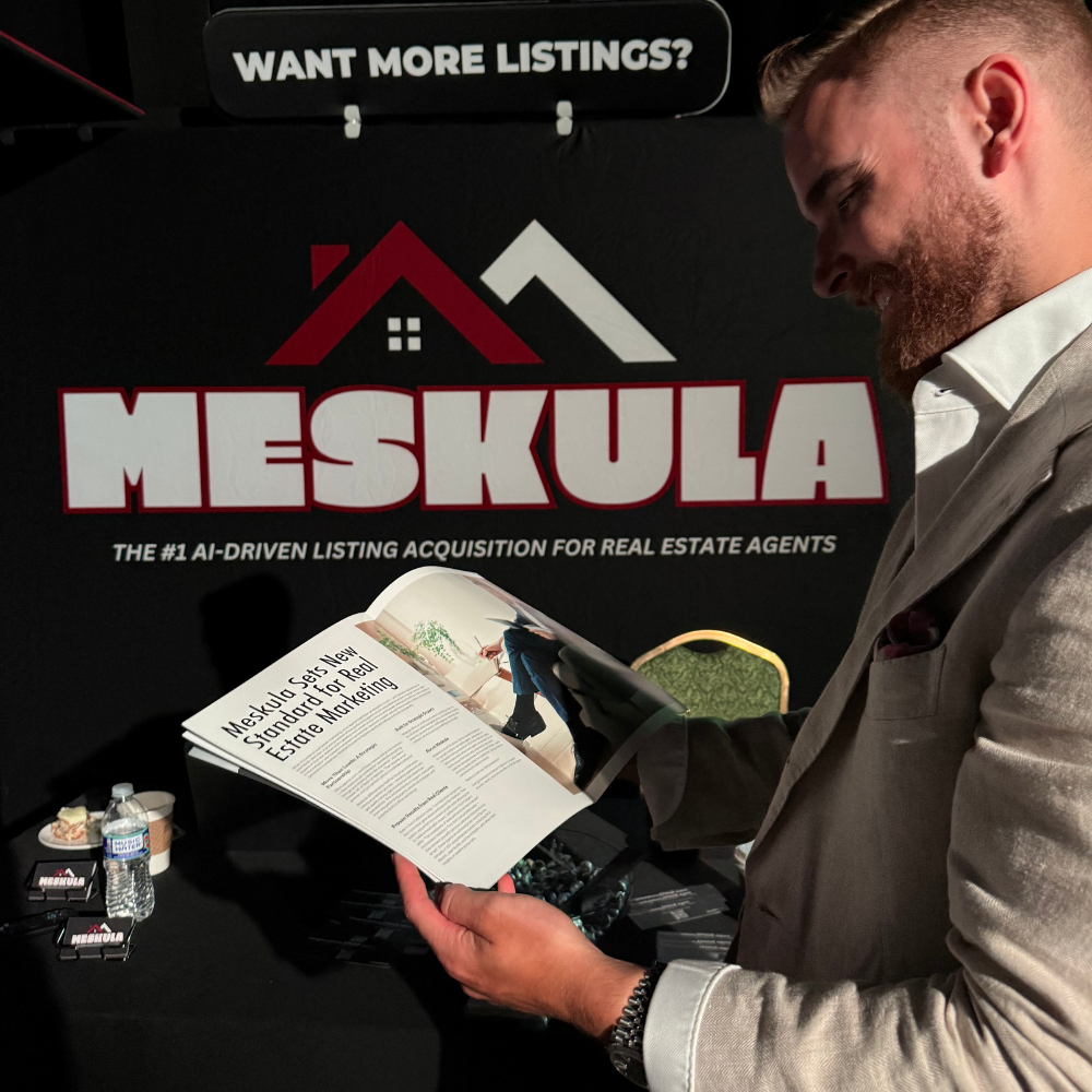 Man in a suit reading a magazine at a Meskula booth with branding and a sign that says 'Want More Listings?' in the background, showcasing AI-driven listing acquisition for real estate agents.