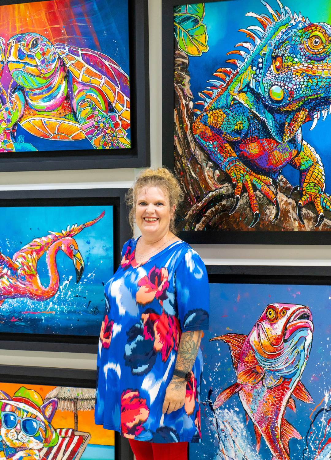 Female artist standing beside her colorful nature-inspired paintings, showcasing her vibrant art collection.