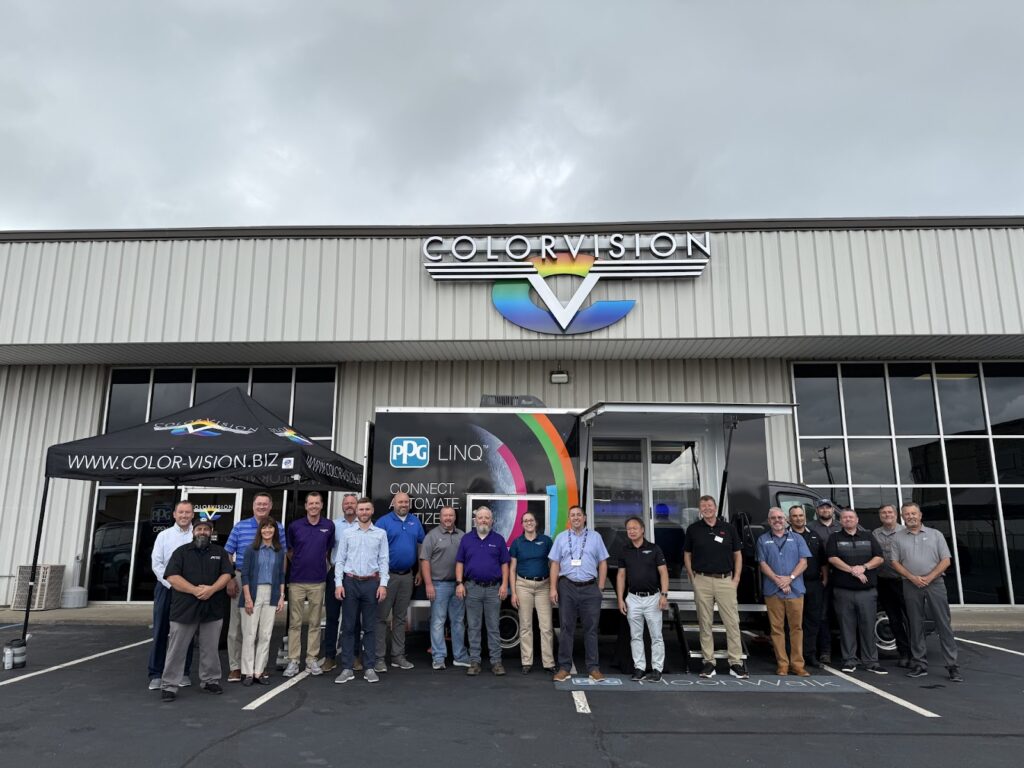 Group of people standing outside Color Vision building under a branded tent and trailer.