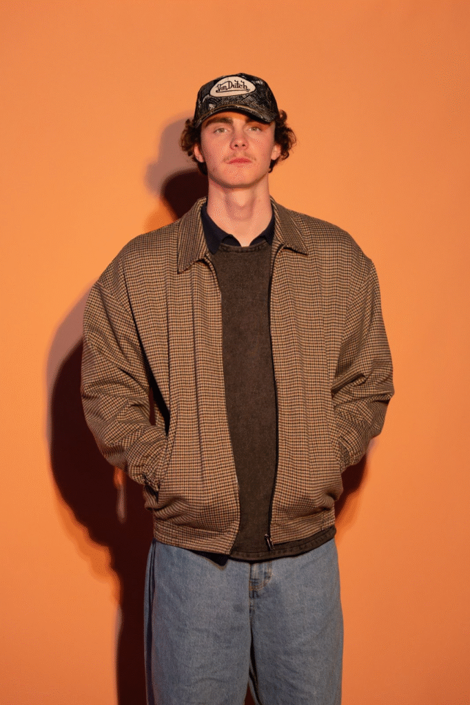 A full-body image of Blake Benson standing confidently, wearing casual yet stylish attire, with a Van Dutch cap, symbolizing his creative and modern approach to music marketing and his dynamic role in reshaping the industry.