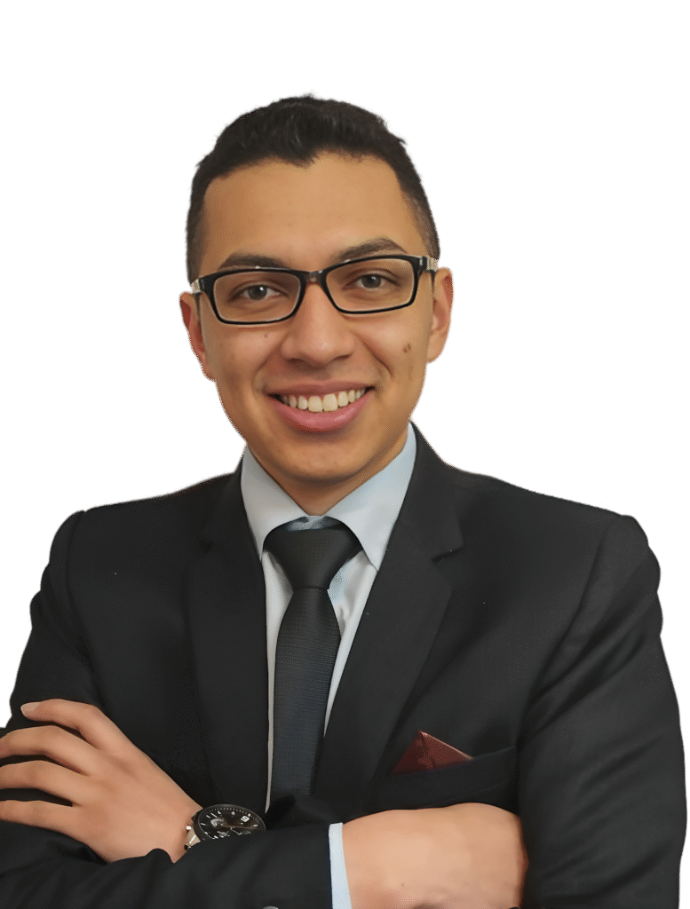 "Professional portrait of a young man in a suit, smiling with glasses and arms crossed, presenting a confident and approachable business image."