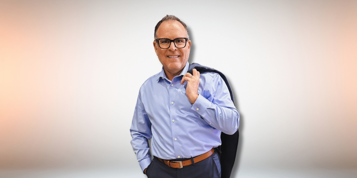 Jim Carlough smiling in a blue shirt and holding a jacket, promoting his leadership development philosophy and book.