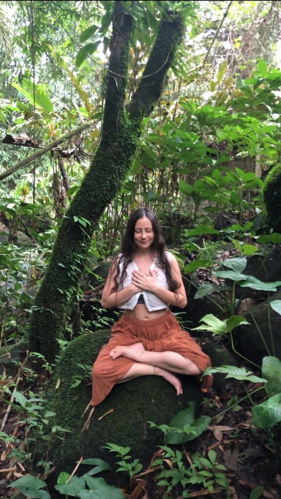 Carla Janse Van Rensburg meditating in nature: Carla practicing meditation in Bali’s lush forest, reconnecting with the earth’s sacred energy.