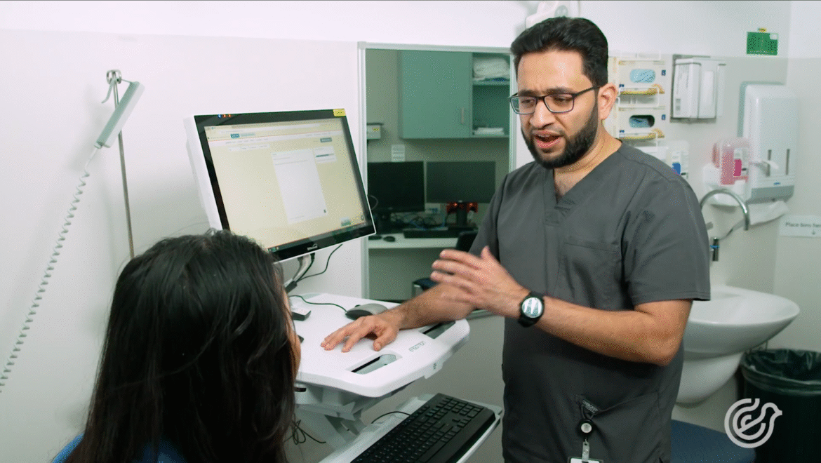 Clinician explaining AI-powered documentation system to colleague in a hospital setting.