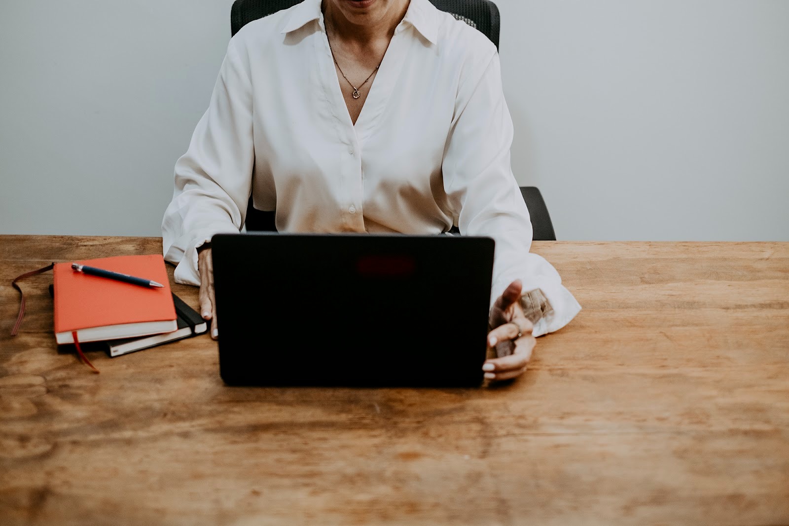 Person working on a laptop, tablet, and notebook, representing digital presence and AI search integration.
