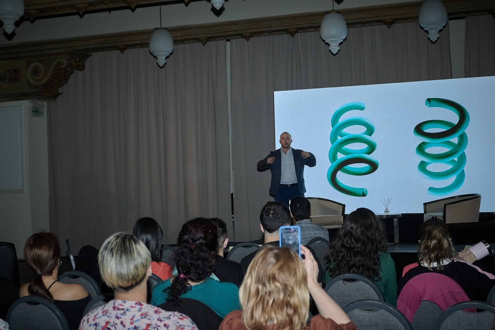 Mateo Silvera speaking at a conference with a presentation in the background.