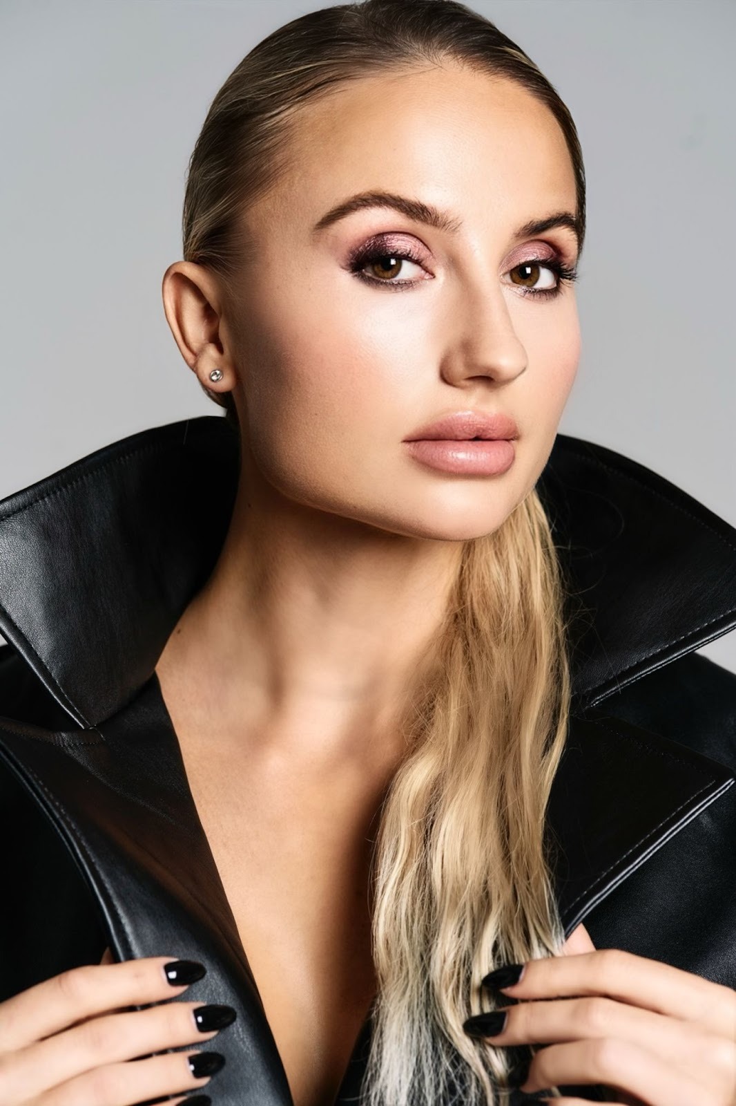 Close-up of MYLA wearing a sleek leather jacket with bold makeup and black nails.