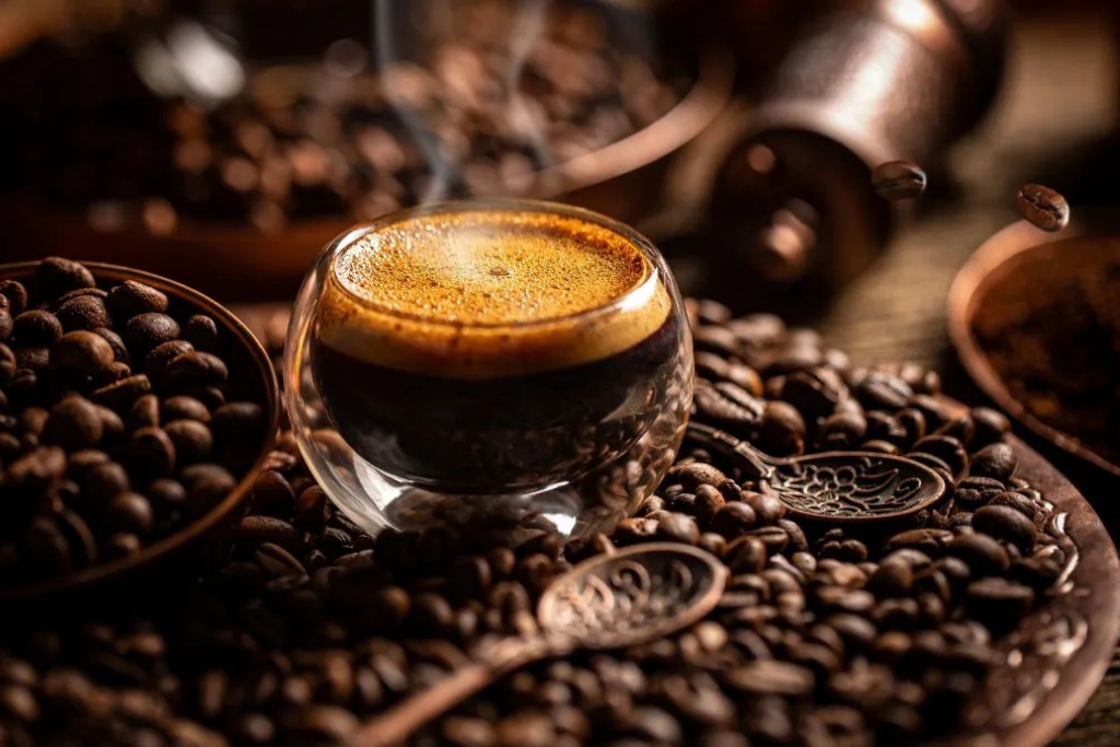 Close-up of a steaming cup of coffee surrounded by roasted coffee beans