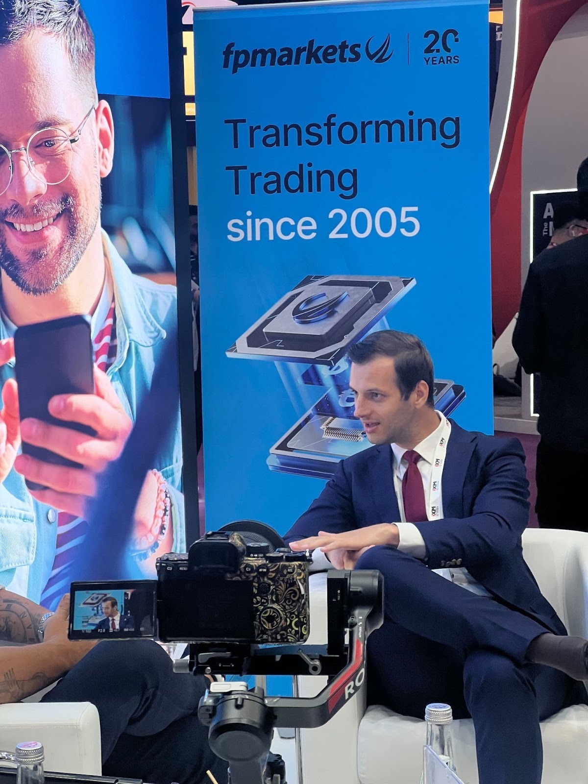 A speaker discussing at the FP Markets booth during the event.