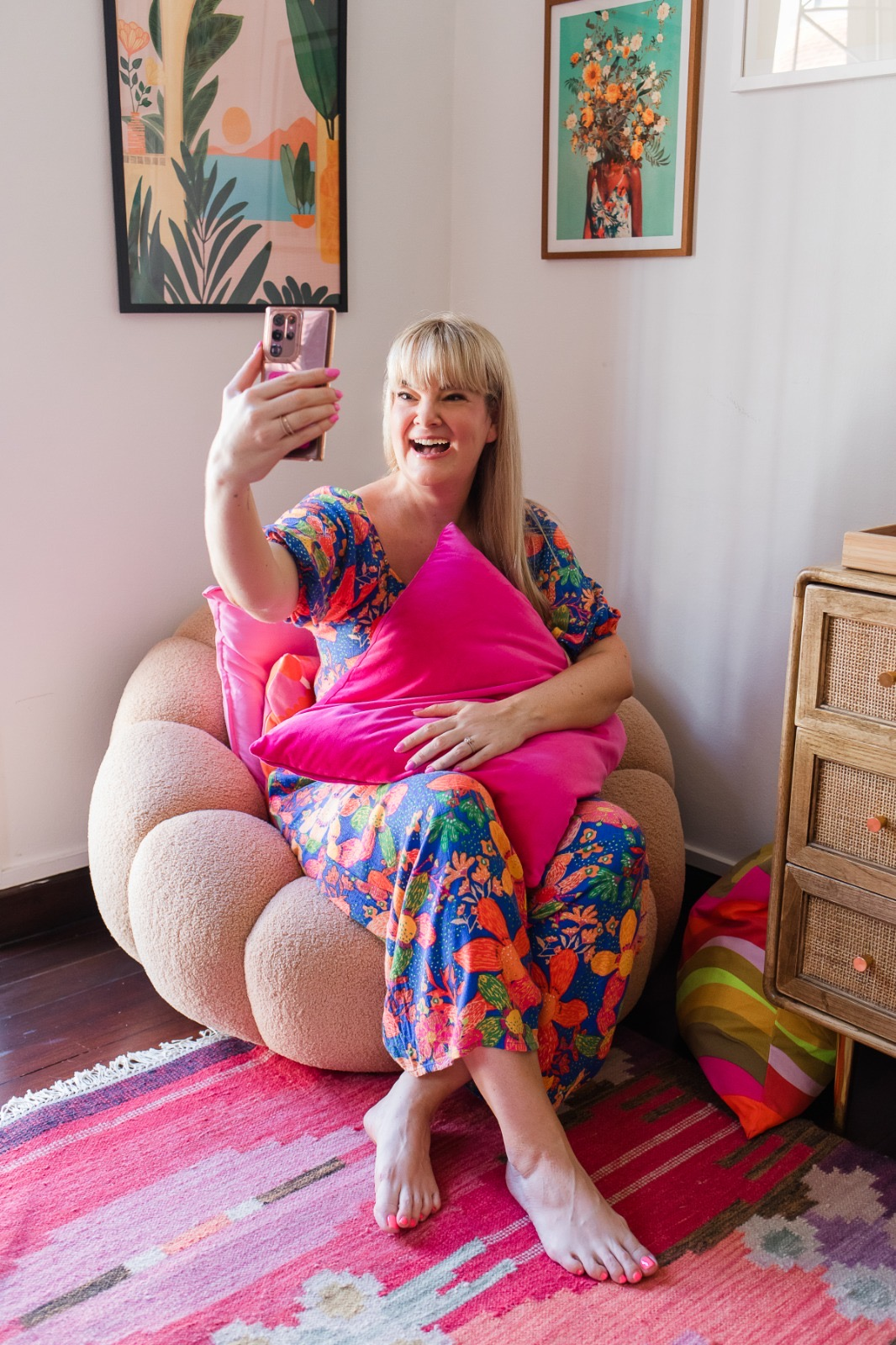 Nikki Smit takes a selfie while sitting on a cozy chair, surrounded by bright pillows.