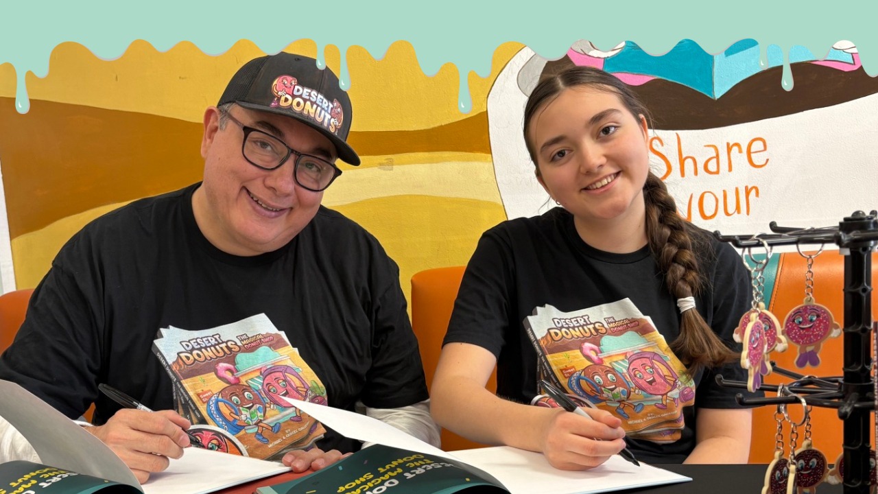 Michael Gallegos and his daughter, Gracee, signing books together at Desert Donuts.