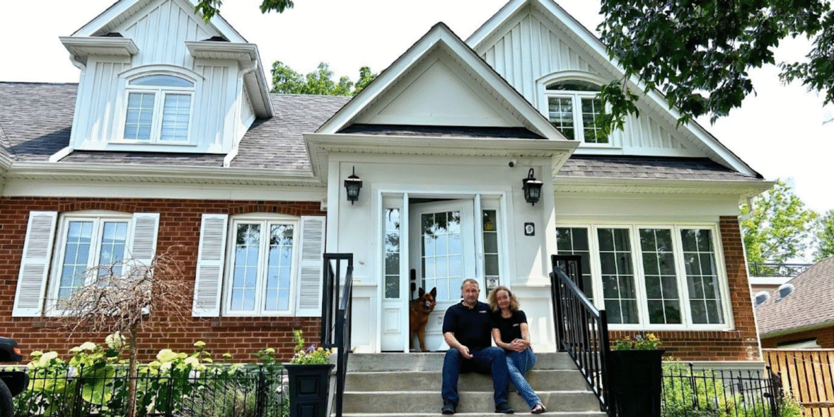 Martin and Beata Kinal, real estate professionals, in front of a home, showcasing their 'Forever Home' initiative linking home buying with pet adoption.