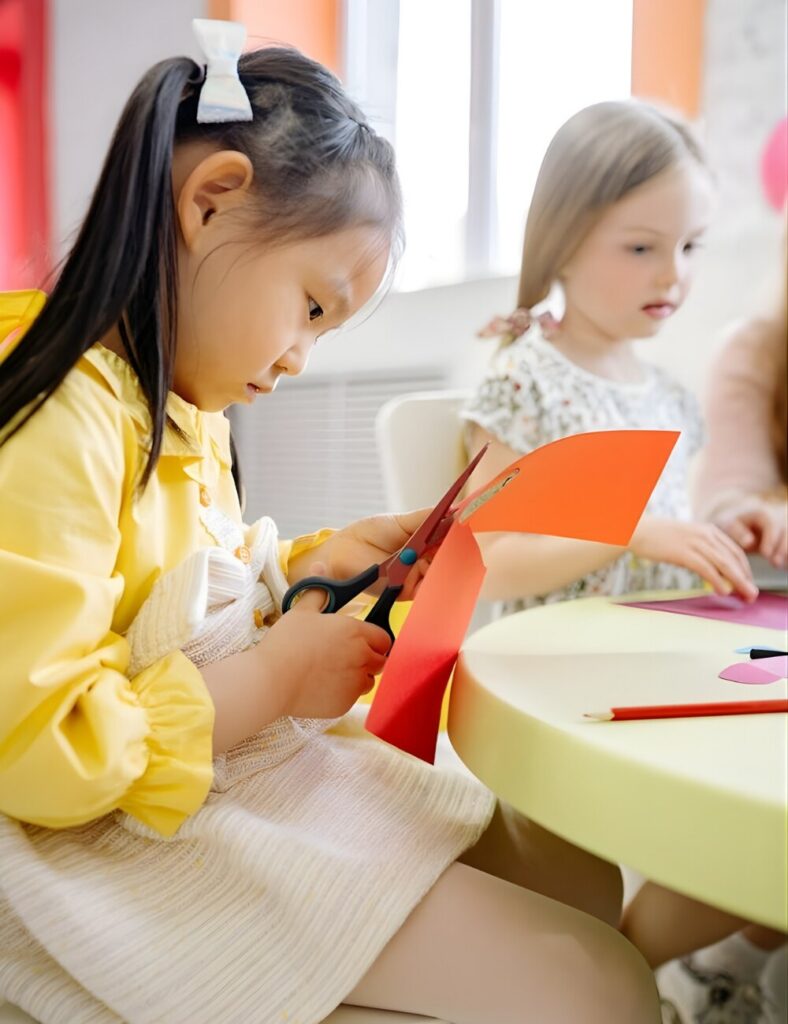 Two children are engaged in cutting colorful paper with scissors, showcasing creativity and hands-on learning.