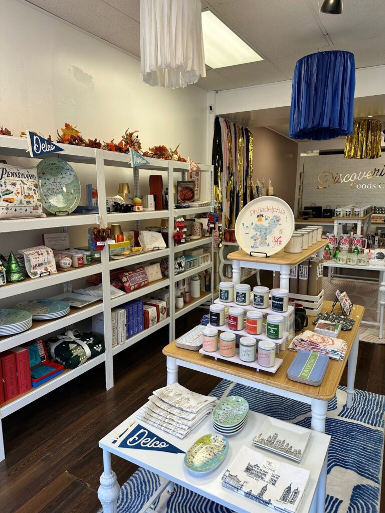 A gift shop interior featuring shelves filled with various items and a blue rug on the floor, inviting shoppers to explore.