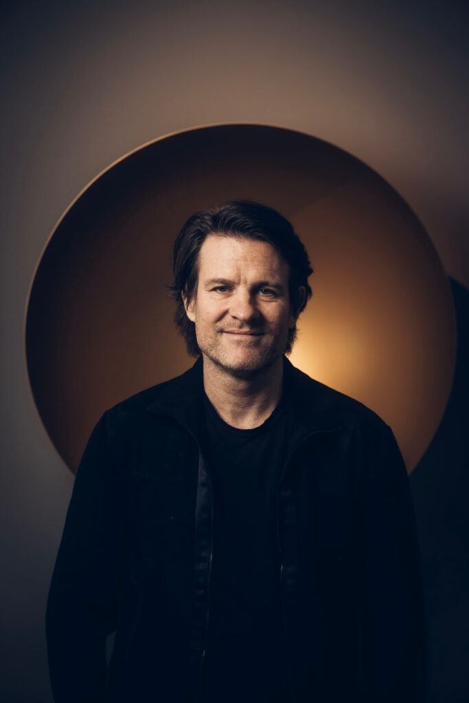 A man stands before a large round light, embodying the insightful approach of Lindqvist Contemporary in navigating the art market.