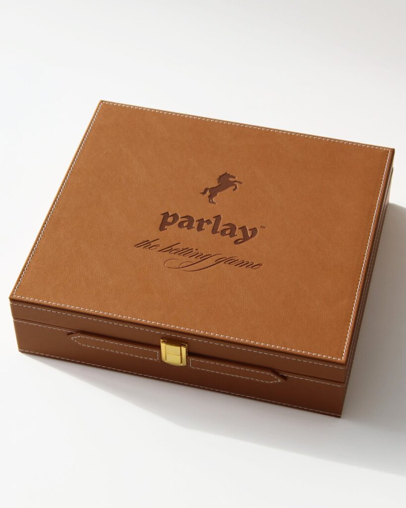 Brown leather box labeled "Parlay," designed for premium social gaming experiences and fostering meaningful connections.