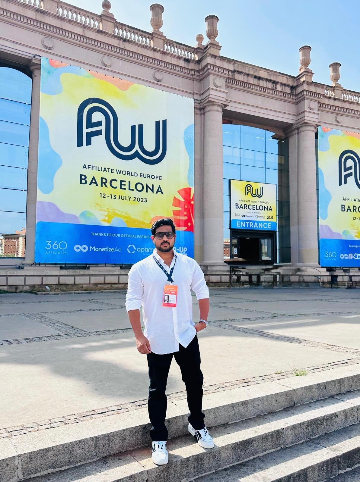 Man with conference badge standing outside Affiliate World Europe Barcelona venue with large event banners.