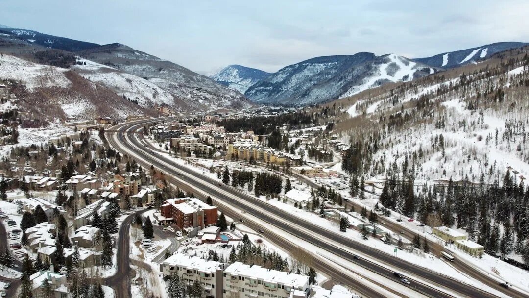 Snow-covered mountain town with highway winding through alpine valley.