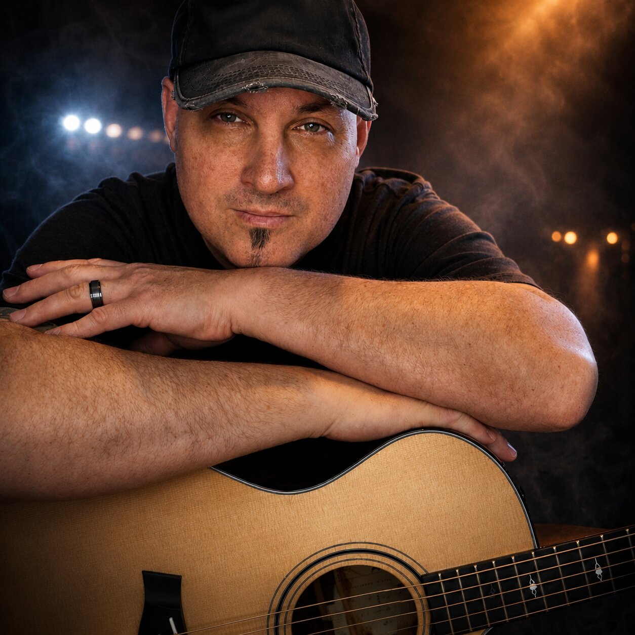 Gene Dozois resting on acoustic guitar in dramatic portrait with moody stage lighting background.