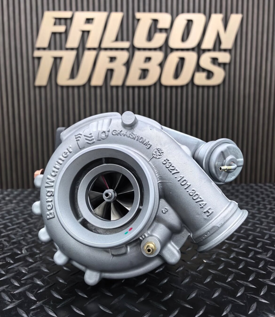 Silver Falcon Turbos hybrid turbocharger displayed on diamond plate surface with Falcon Turbos logo background.