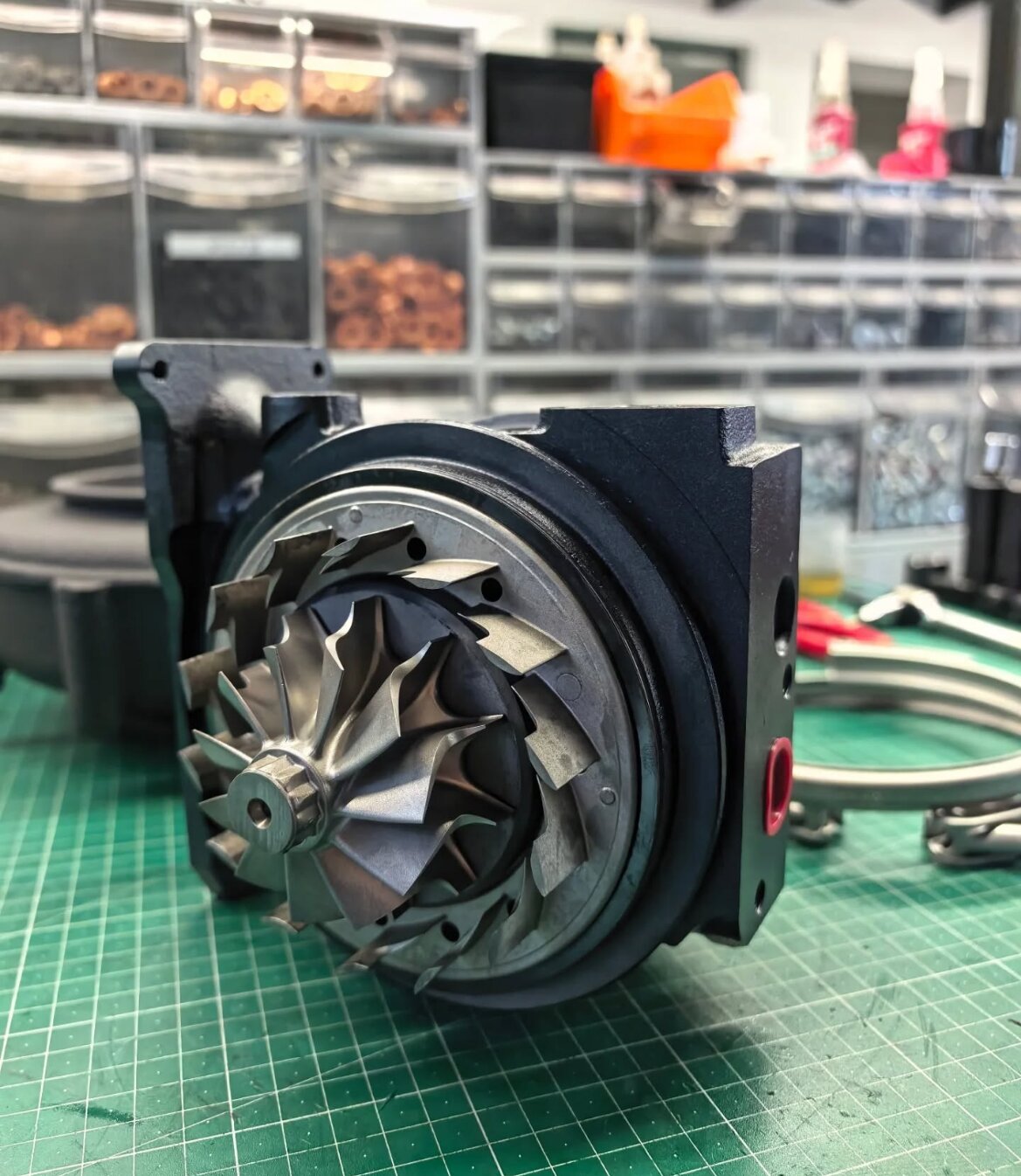 Precision-engineered Falcon Turbos hybrid turbocharger on workshop bench with organized performance components in background.