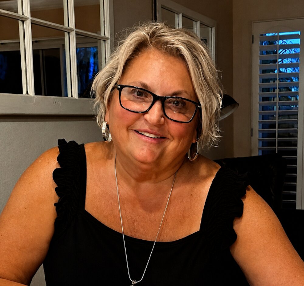 Smiling woman with short gray hair and glasses, founder Tammy Collinsworth of TLC Grief Coach.