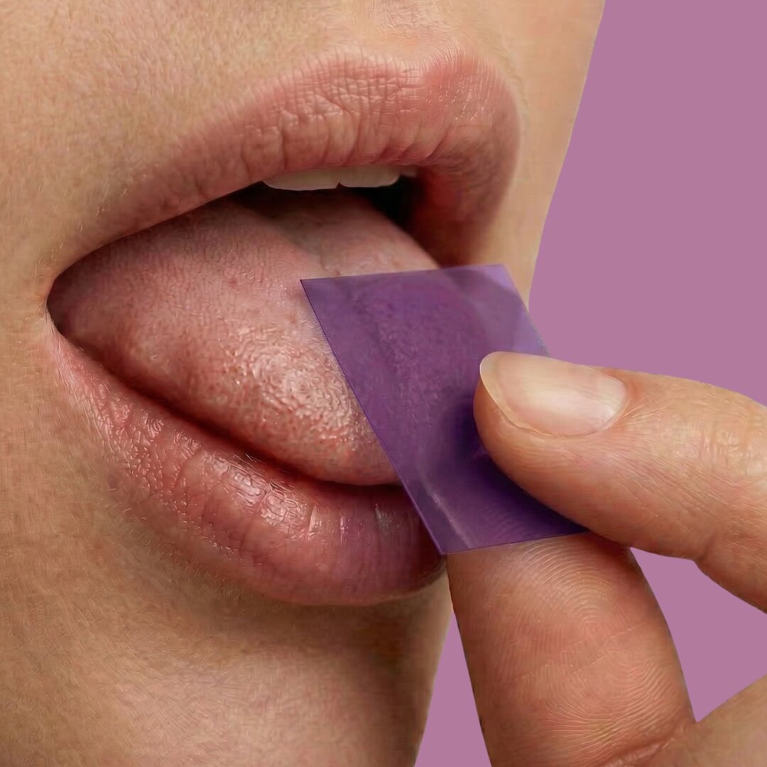 Person placing a dissolvable MedHugs vitamin strip on their tongue as an alternative to pills and gummies.